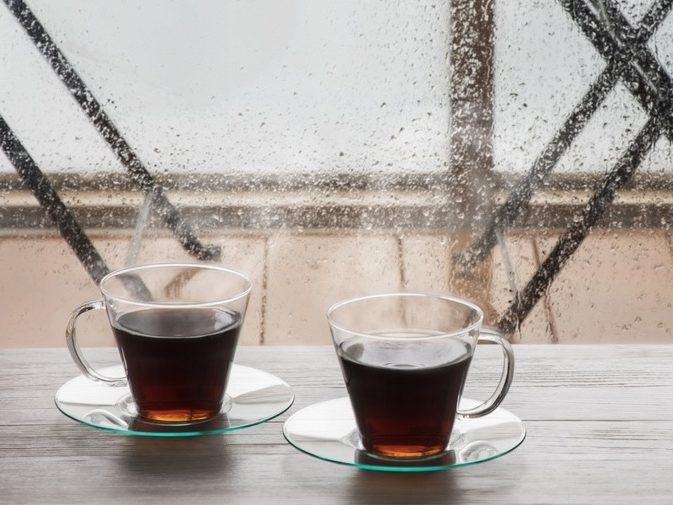 Two cups of tea side by side by a rainy window